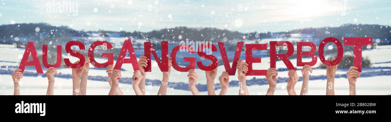 Persone mani tenuta Parola Ausgangsverbot significa coprifuoco, neve sfondo invernale Foto Stock