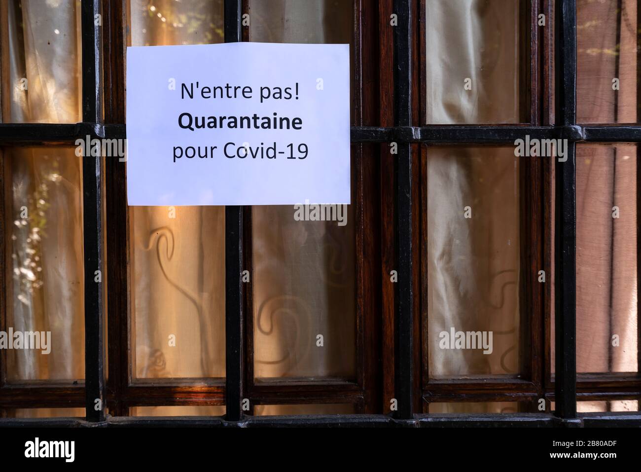 Il segno con il divieto di ingresso per la quarantena per il virus Covid-19 in lingua francese su una finestra principale Foto Stock