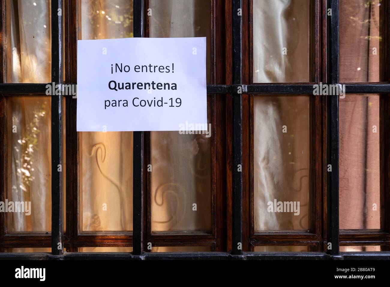 Il segno con il divieto di ingresso per la quarantena per il virus Covid-19 in lingua spagnola su una finestra principale Foto Stock