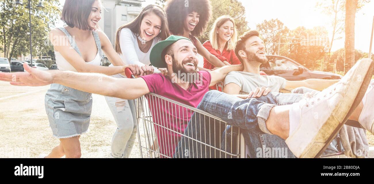 Giovani millennials persone che corrono con il carrello - amici folli felici divertirsi con i carrelli nel parcheggio - stile di vita giovanile e concetto di festa - Fo Foto Stock