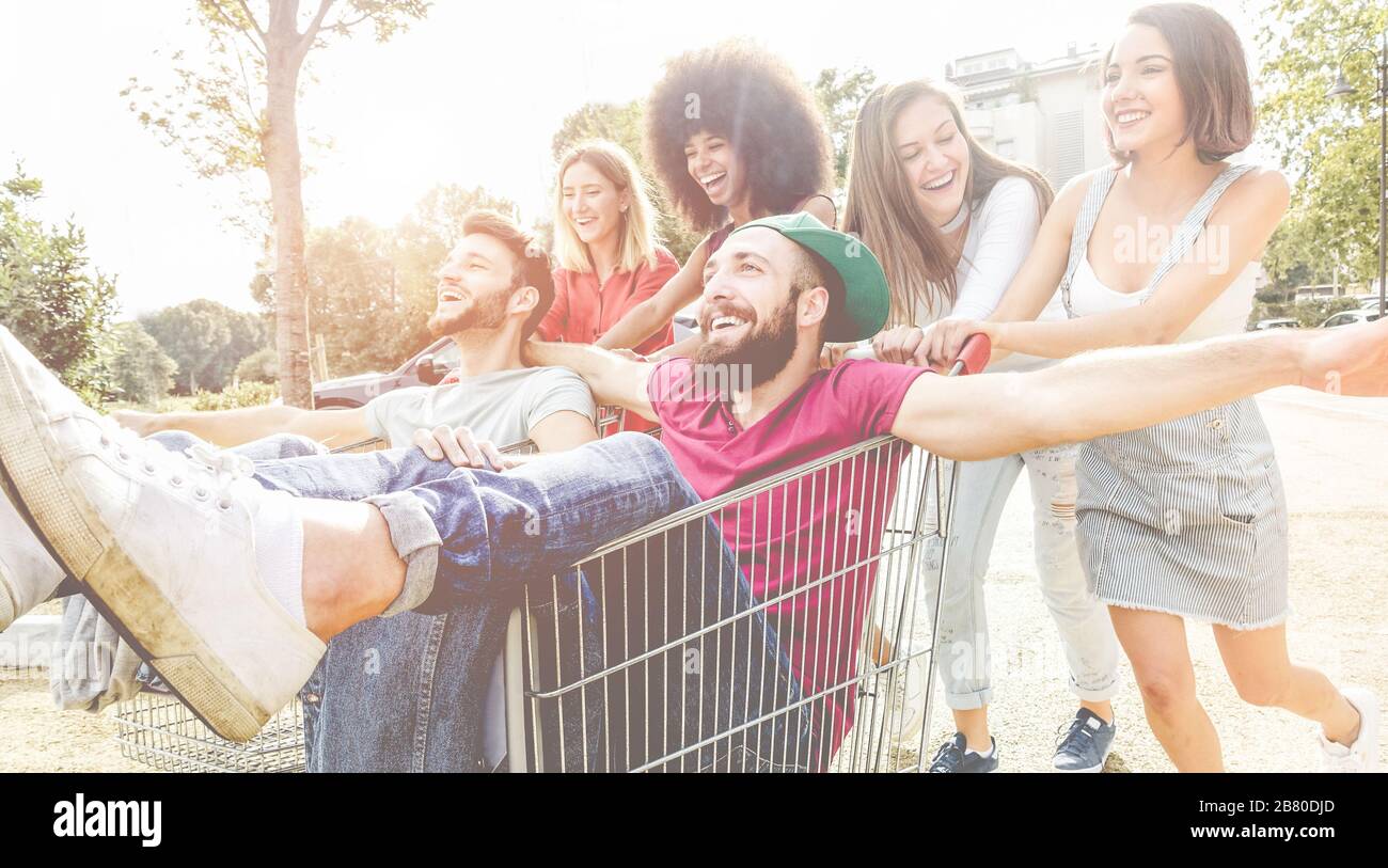 Giovani millennials persone che corrono con il carrello - amici folli felici divertirsi con i carrelli nel parcheggio - stile di vita giovanile e concetto di festa - Fo Foto Stock