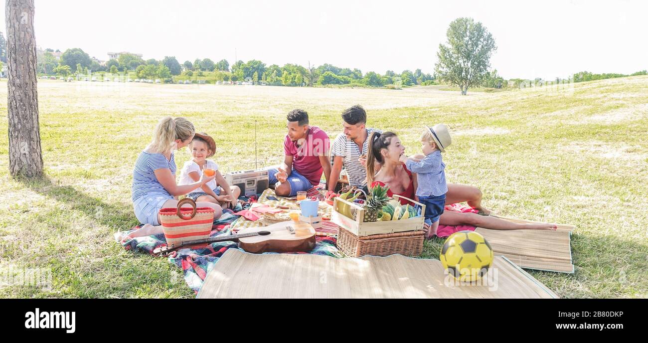 Famiglie felici fare picnic nel parco della città - i giovani genitori che si divertono con i loro bambini in estate mangiare, ridere e giocare insieme - Amore a Foto Stock