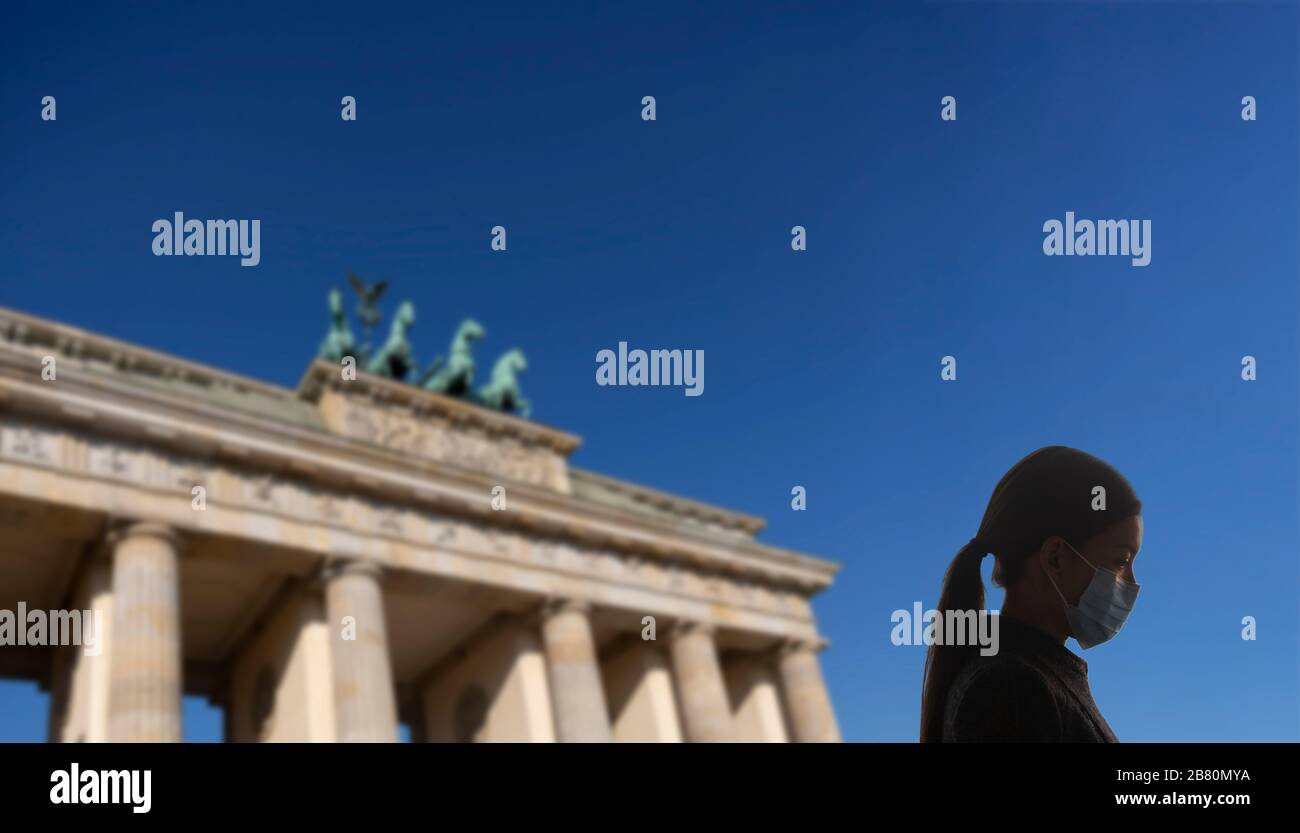 Coronavirus a Berlino, Germania, Europa. Donna con maschera chirurgica per la protezione del virus corona covid-19 a Berlino di fronte alla porta di Brandeburgo / Brandenburger Tor. Composito. Foto Stock