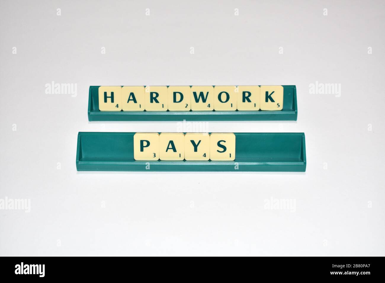 Le piastrelle Scrabble spell out hardwork Pays. Citazione motivazionale blocchi Scrabble lettere Grigio sfondo citazione di vita indurre alfabeto. Foto Stock