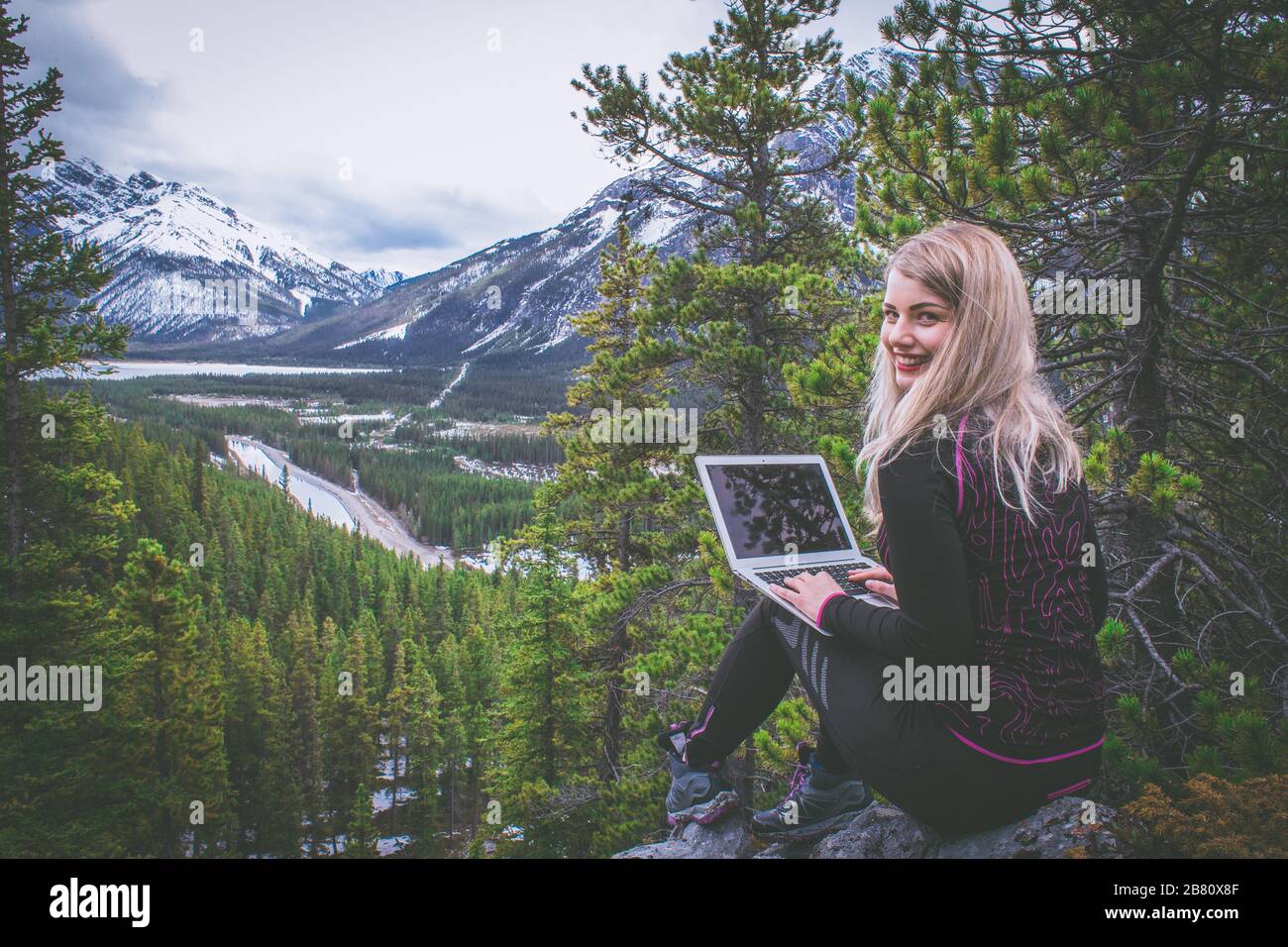 Donna nomade digitale che lavora sul suo laptop in montagna Foto Stock