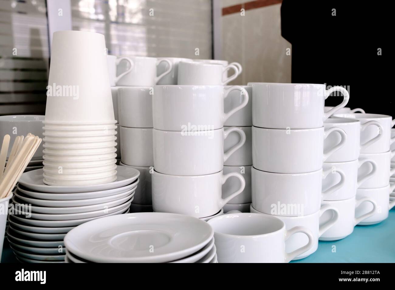 Esposti su pile di tazze bianche e piattini in ceramica pulita. I piatti del ristorante sono preparati per bere il tè e il caffè. Foto Stock