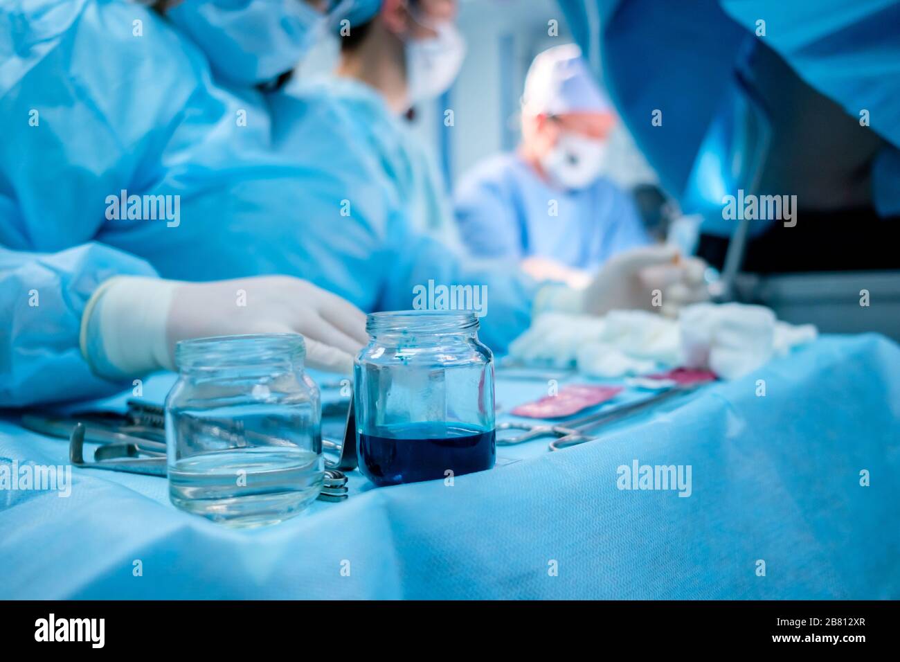 Strumenti chirurgici sterili e contenitori in vetro con soluzioni speciali sul tavolo durante un intervento chirurgico. Su uno sfondo molto sfocato, surgeo Foto Stock