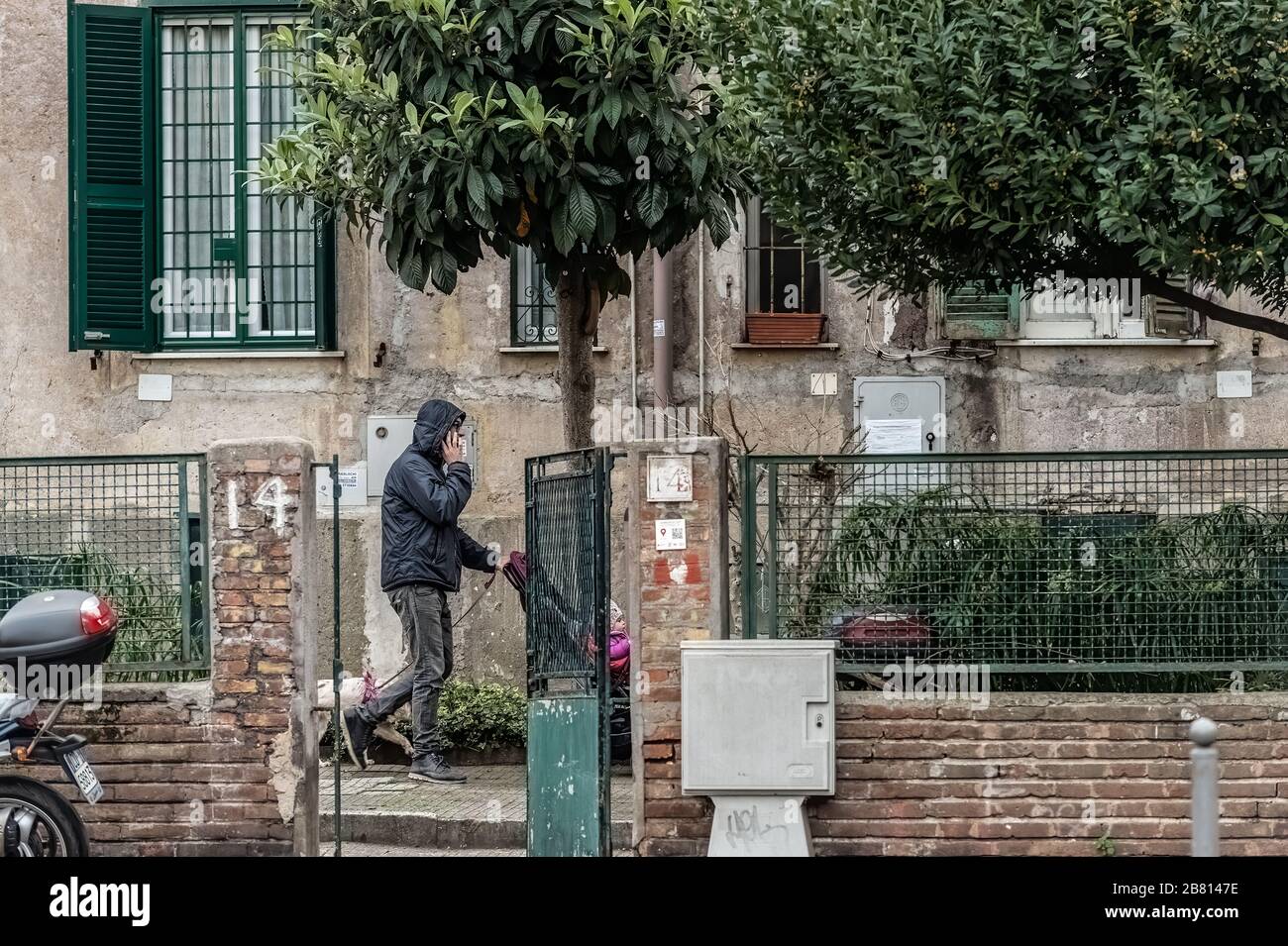 Un padre si avvale del piccolo giardino della sua casa nel popolare quartiere Garbatella di Roma, per prendere suo figlio per una passeggiata in carrozzina durante l'epidemia di Coronavirus che ha colpito pesantemente l'Italia. Il governo italiano ha costretto tutti i cittadini a rimanere nelle loro case, tranne per comprovate ragioni di lavoro, salute e di acquistare cibo e altri beni essenziali. Foto Stock