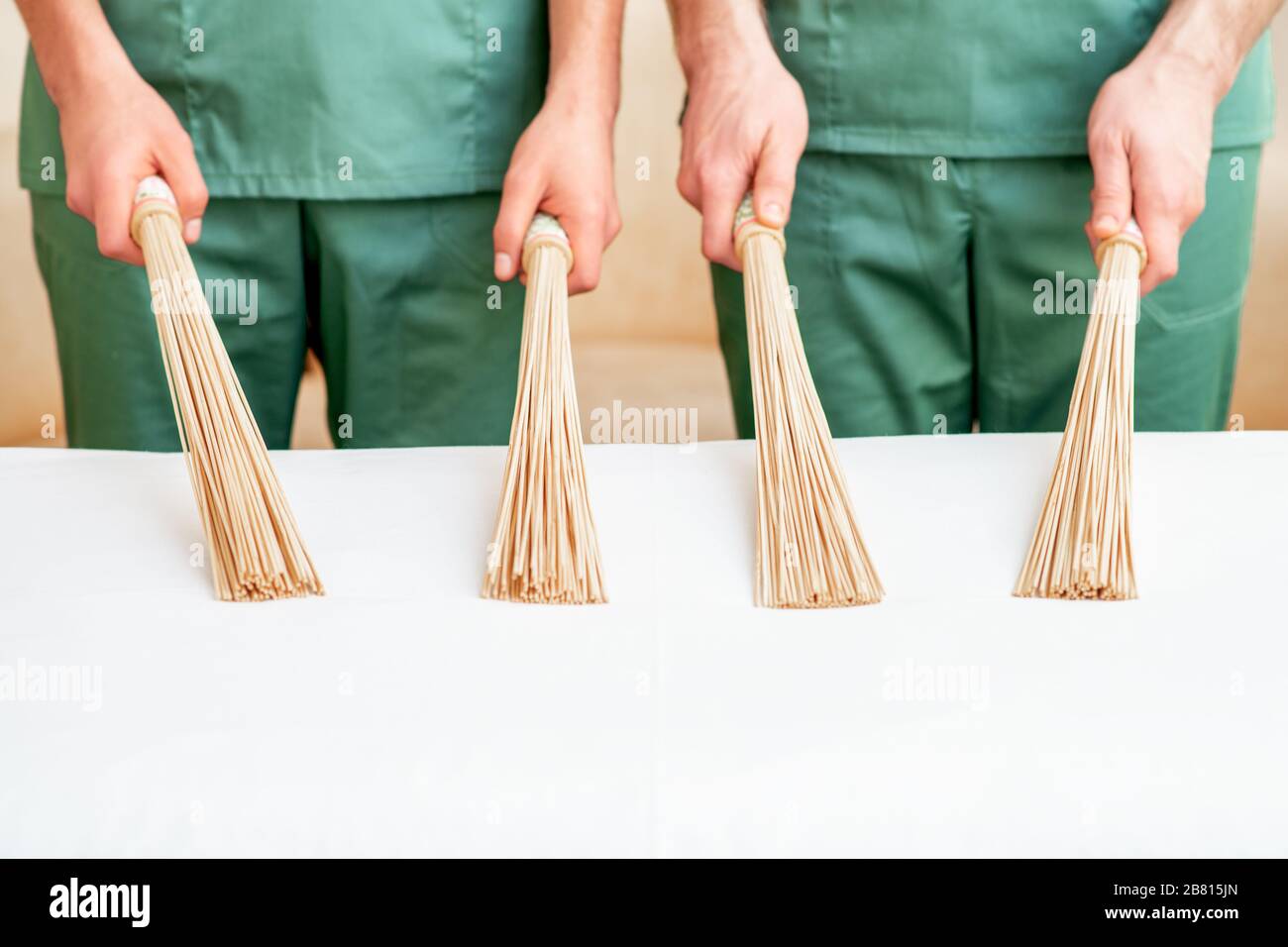 Massaggiate le ginestra di bambù in mano a due massaggiatori. Foto Stock