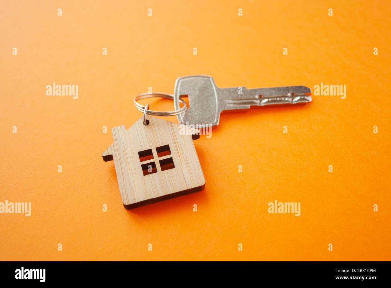 Disposizione portachiavi a forma di chiave e di casa su sfondo arancione. Vista dall'alto, disposizione piatta. Immobiliare, concetto di assicurazione, ipoteca, comprare vendere casa, realtor Foto Stock