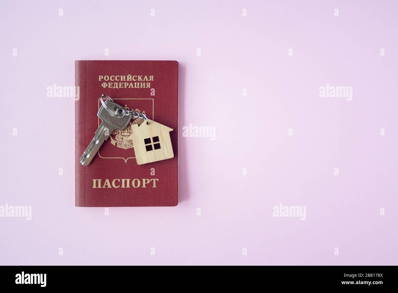 Russian International Passport e chiave con trinket casa su di esso su sfondo rosa primo piano su copia spazio. Immigrazione, emigrazione, cittadinanza Foto Stock