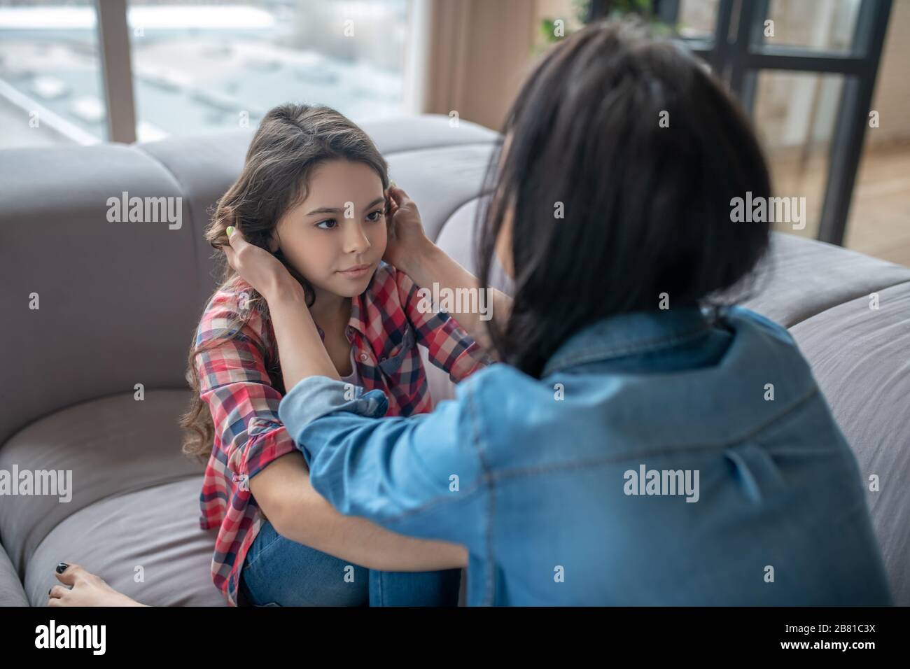 Mamma che tocca le sue tristi figlie affrontare con tenerezza Foto Stock