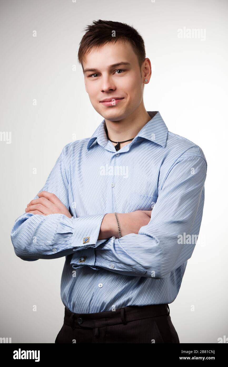 Ragazzo con capelli corti di colore marrone vestito con camicia blu e  pantaloni neri, posando con le braccia incrociate sul petto. Isolato su  sfondo bianco Foto stock - Alamy
