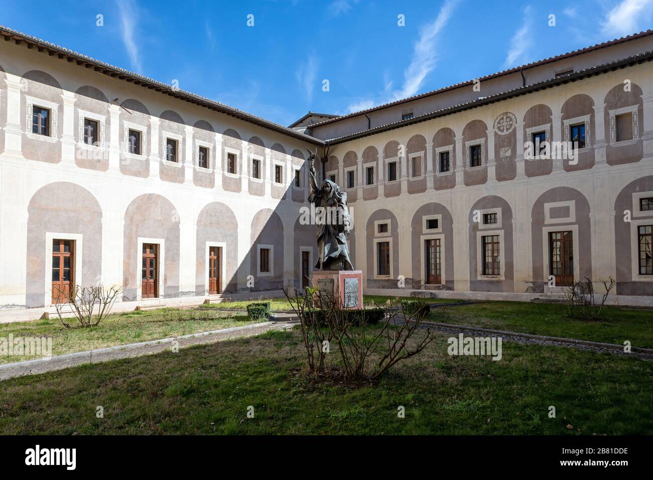 Subiaco, Italia - 23 febbraio 2020: L'antico chiostro rinascimentale con il giardino e la statua di Santa Scolastica, all'interno del monastero. Foto Stock