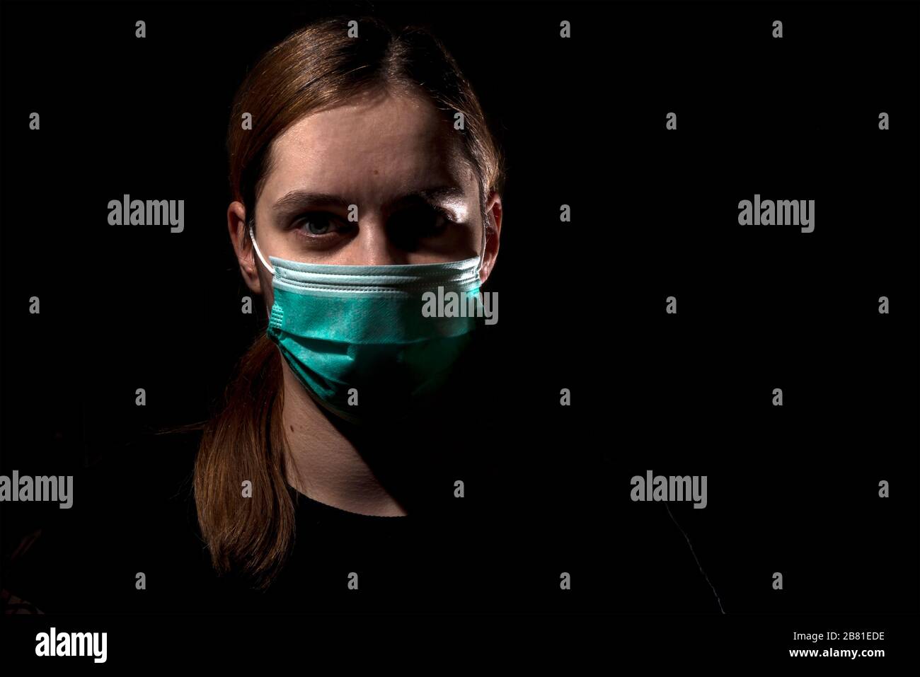 Donna che indossa maschera per la protezione del virus corona covid-19 SARS-cov-2, donna con maschera su sfondo nero Foto Stock