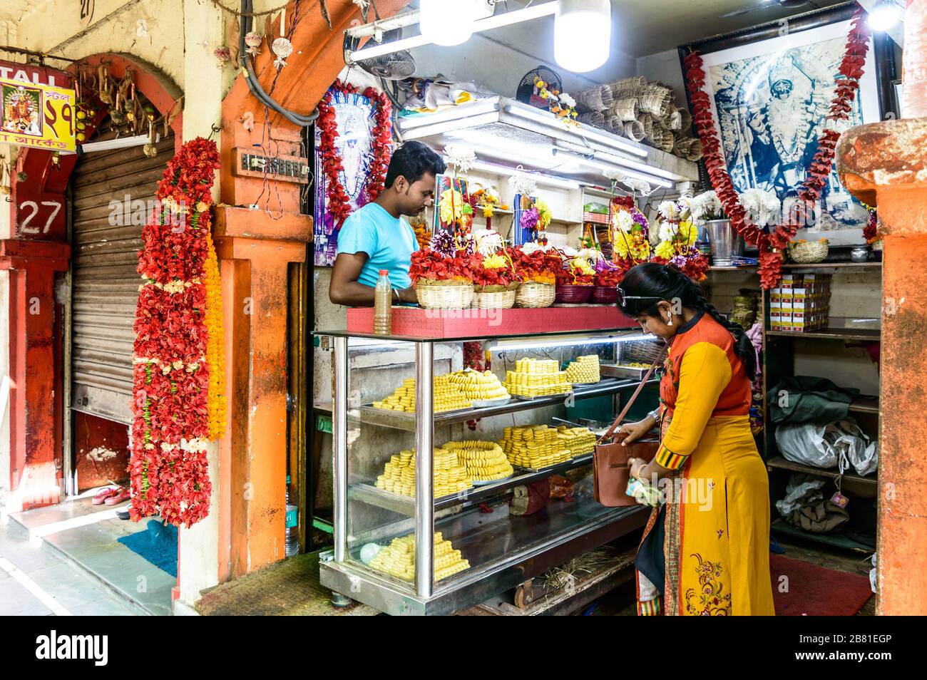 Una bancarella del mercato che mostra oggetti Puja devozionale indù o offerte religiose, fiori di cibo dolce a Dakshineswar Kali Temple Street store Kolkata West BE Foto Stock