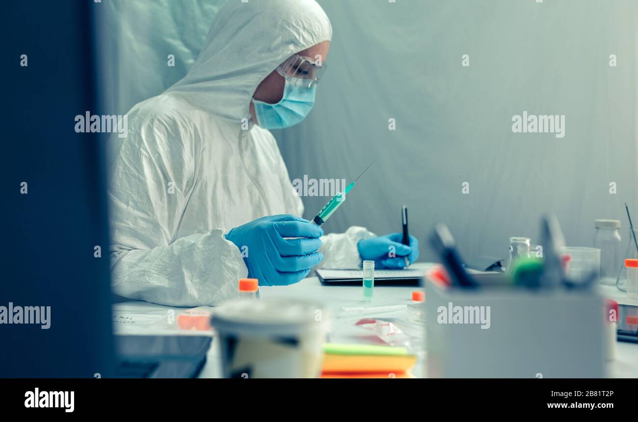 Scienziato con tuta di protezione che indaga un vaccino in laboratorio Foto Stock