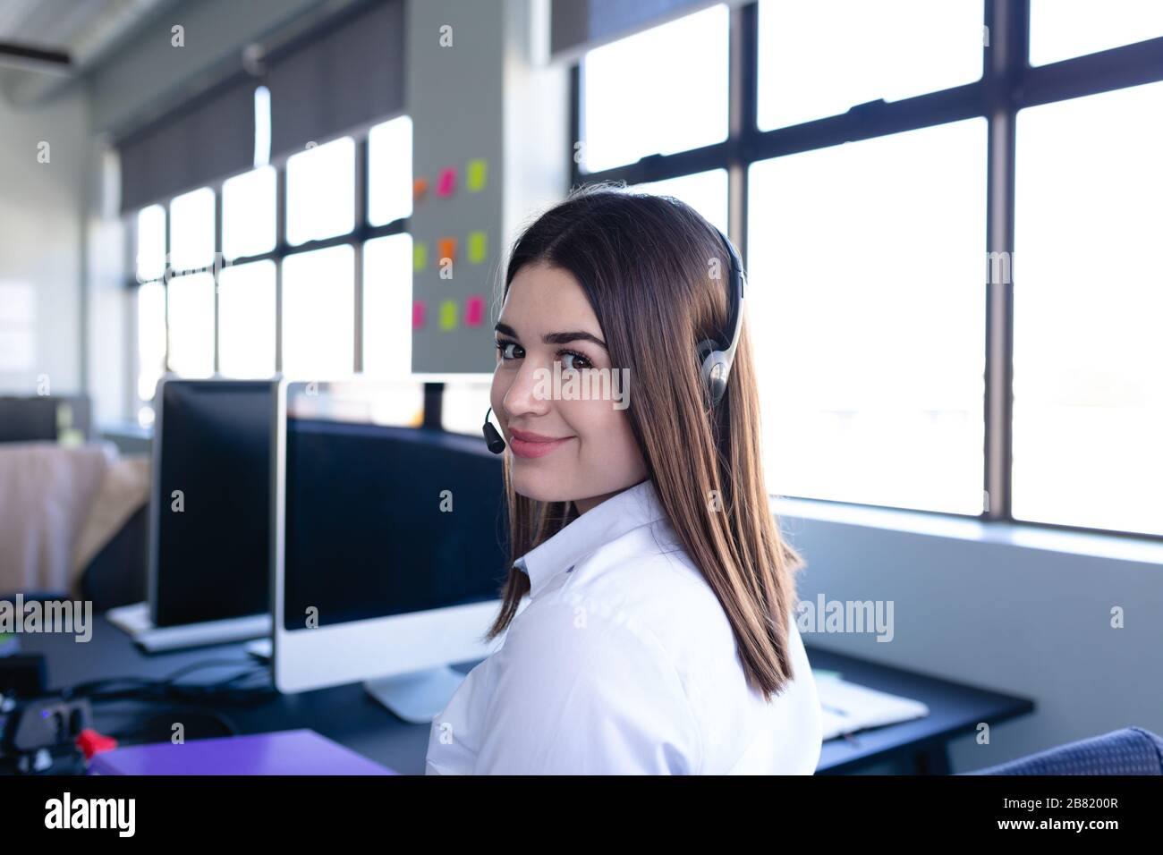 Donna caucasica che lavora con un set di cuffie Foto Stock
