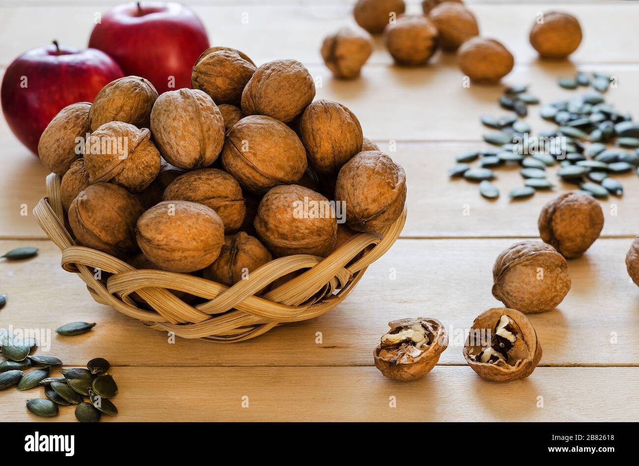 noci in un cesto, mele e semi di zucca su uno sfondo di albero Foto Stock