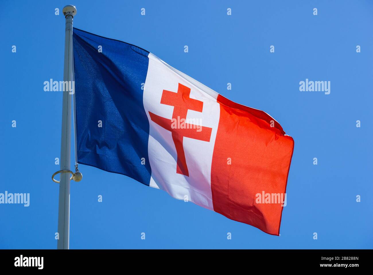 Rosso Lorraine croce su una bandiera francese ondeggiante contro il cielo blu. Simbolo Général de Gaulle della seconda Guerra Mondiale. Foto Stock