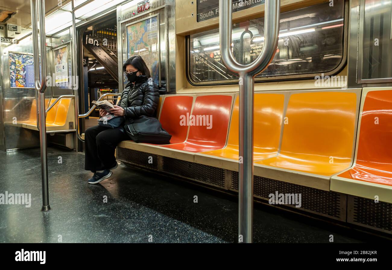 Una donna indossa una maschera chirurgica in una macchina metropolitana quasi vuota a New York il mercoledì 18 marzo 2020. Il ridership della metropolitana è sceso del 60% a causa della pandemia del covid-19 e l'MTA sta cercando un salvataggio da 4 miliardi di dollari. (© Richard B. Levine) Foto Stock