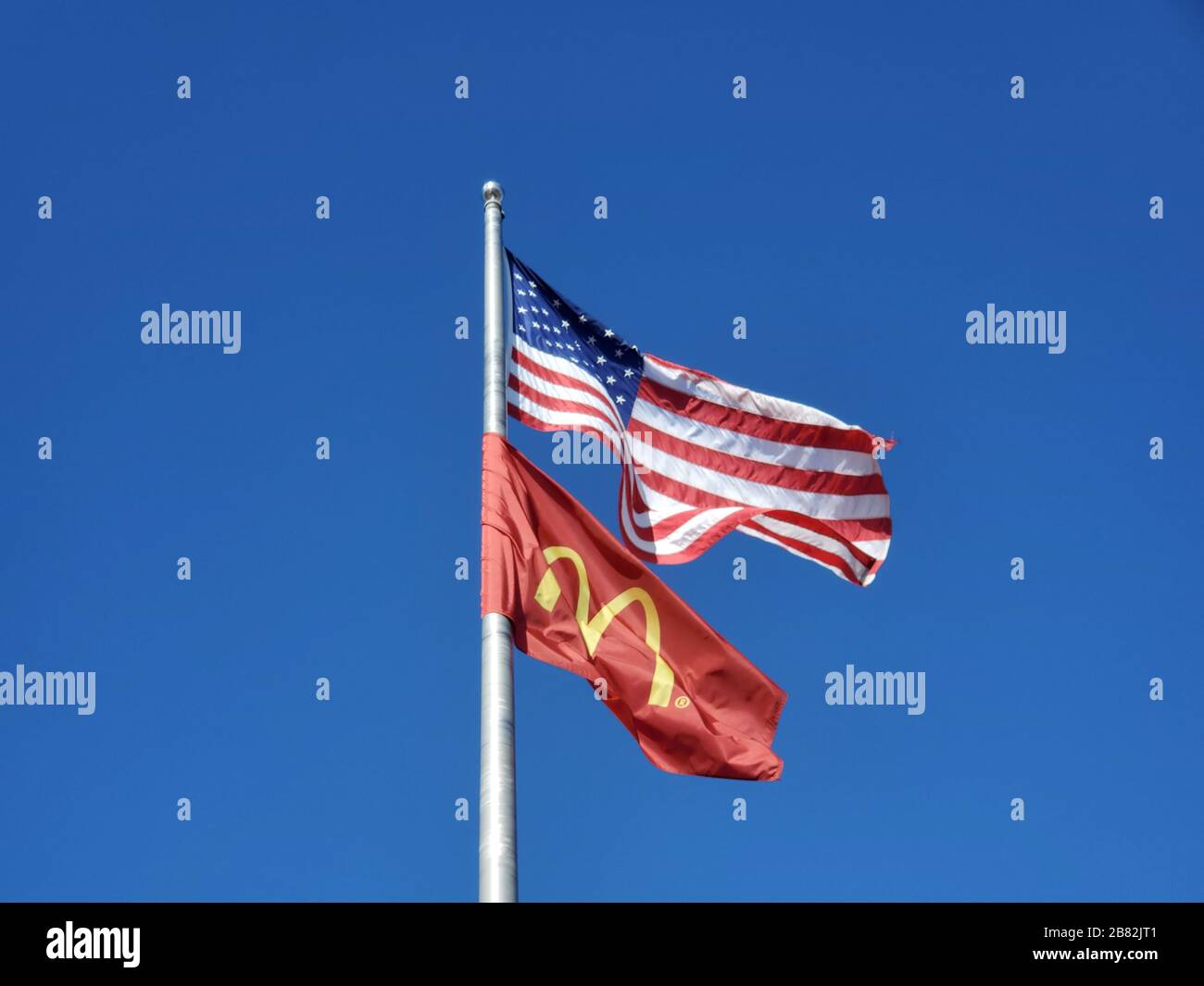 Primo piano del flagpole contro il cielo blu battenti bandiera americana e bandiera con il logo della McDonald's Corporation, Dublino, California, 23 febbraio 2020. () Foto Stock