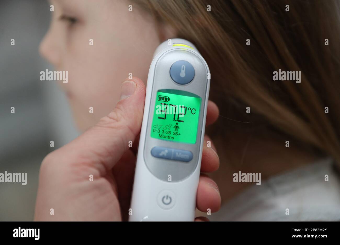 Una temperatura del bambino di 37.2 gradi è presa usando un termometro dell' orecchio Foto stock - Alamy