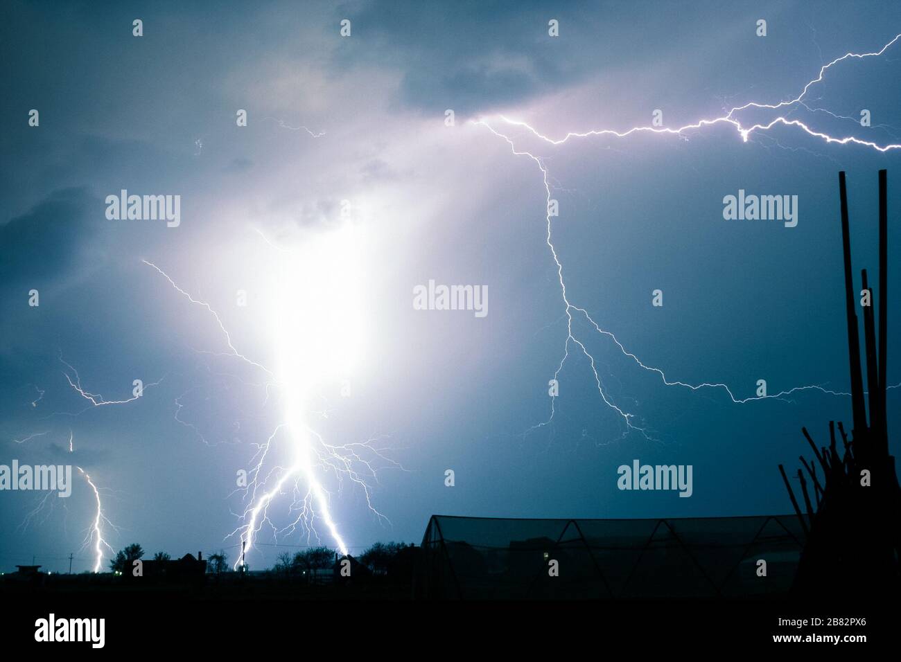 Incredibile mostra di fulmine accecanti con molti rami laterali che colpiscono la terra Foto Stock