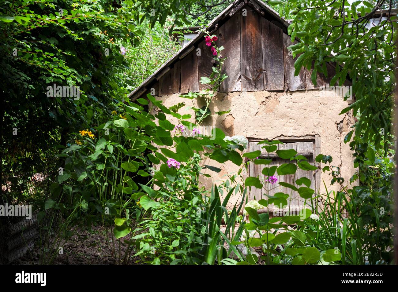 Vecchia casa di capra con porta di legno in un giardino di campagna Foto Stock