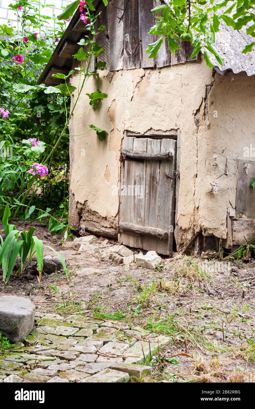Vecchia casa di capra con porta di legno in un giardino di campagna Foto Stock