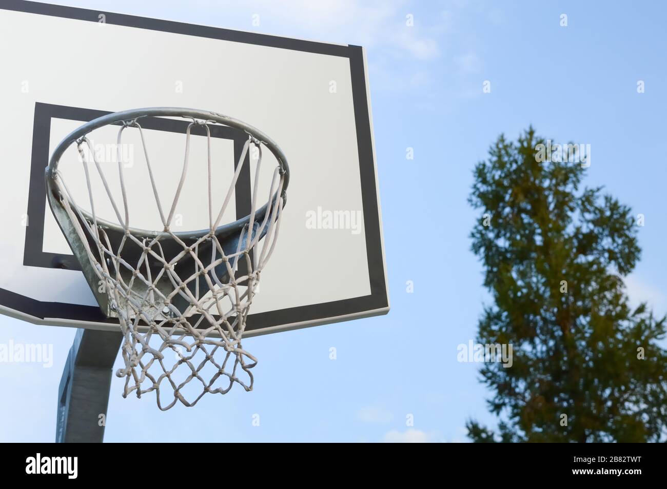 basket backboard con un cesto su un cielo blu e verde albero sfondo, concetto di sport, stile di vita attivo e attività ricreative all'aperto Foto Stock