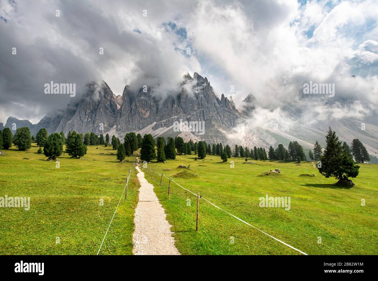 Sentiero escursionistico al Gschnagenhardt Alm, cime di Geisler coperte di nuvole, gruppo di Geisler con Sass Rigais, Val di Villnoess, Dolomiti, Alto Adige, Italia Foto Stock