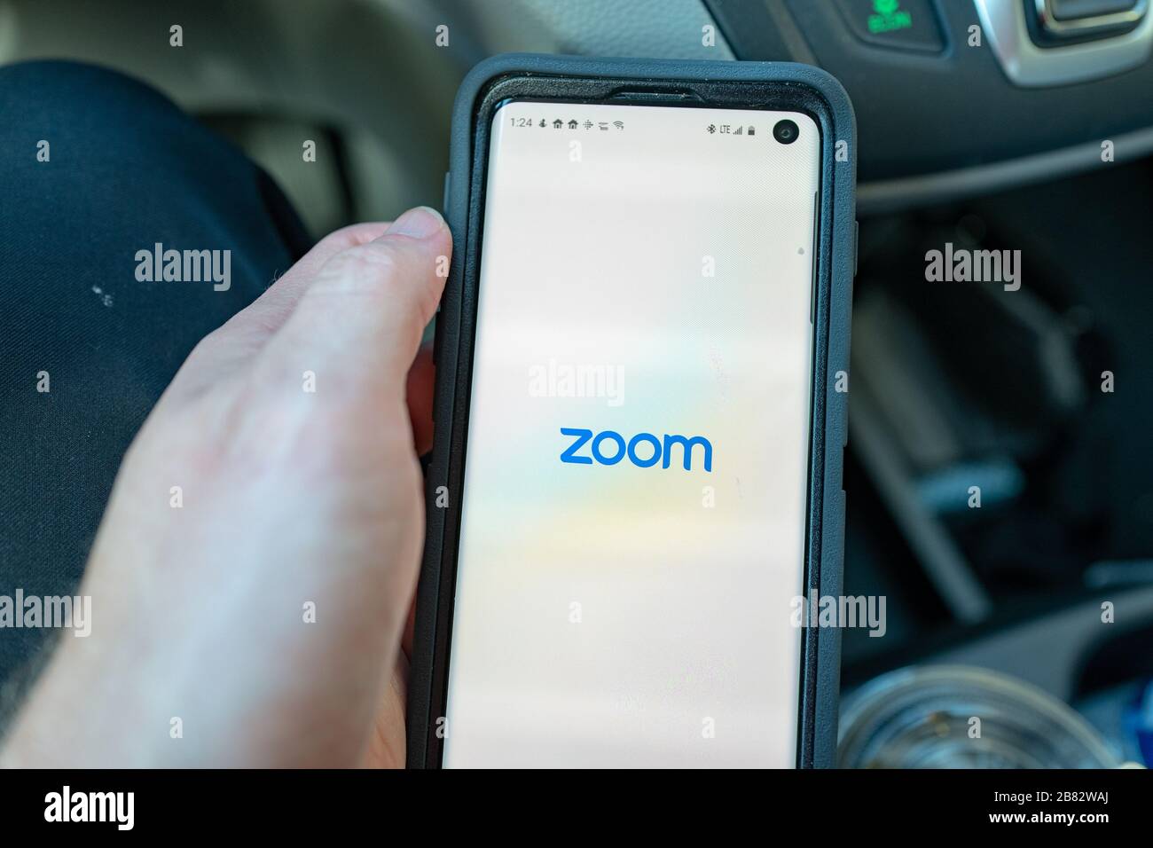 Primo piano di mano di un uomo in possesso di uno smartphone Samsung Galaxy S10 con app per il telelavoro e conferenza società di chiamata Zoom, Walnut Creek, California, 11 marzo 2020. In presenza di uno scoppio del coronavirus COVID-19, molte aziende hanno consigliato ai dipendenti di lavorare in remoto, portando a forti performance finanziarie da parte delle società di telelavoro. () Foto Stock
