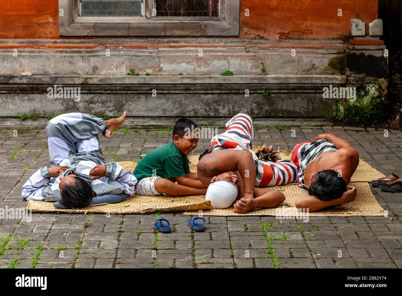 Un bambino gioca con alcuni degli artisti prima DI UNO spettacolo di danza tradizionale Balinese Barong e Kris, Batabulan, Bali, Indonesia. Foto Stock