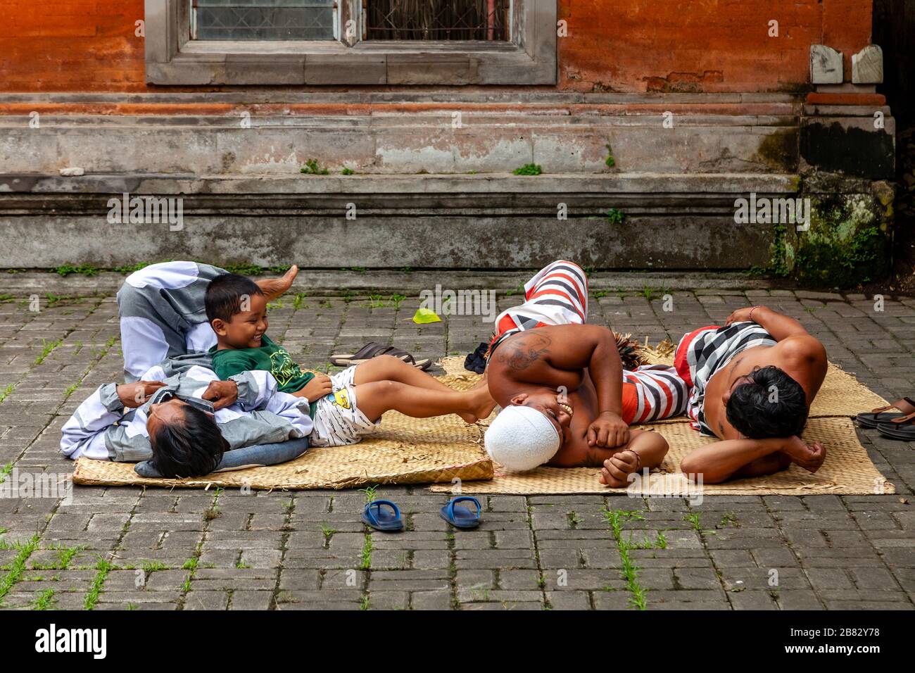 Un bambino gioca con alcuni degli artisti prima DI UNO spettacolo di danza tradizionale Balinese Barong e Kris, Batabulan, Bali, Indonesia. Foto Stock