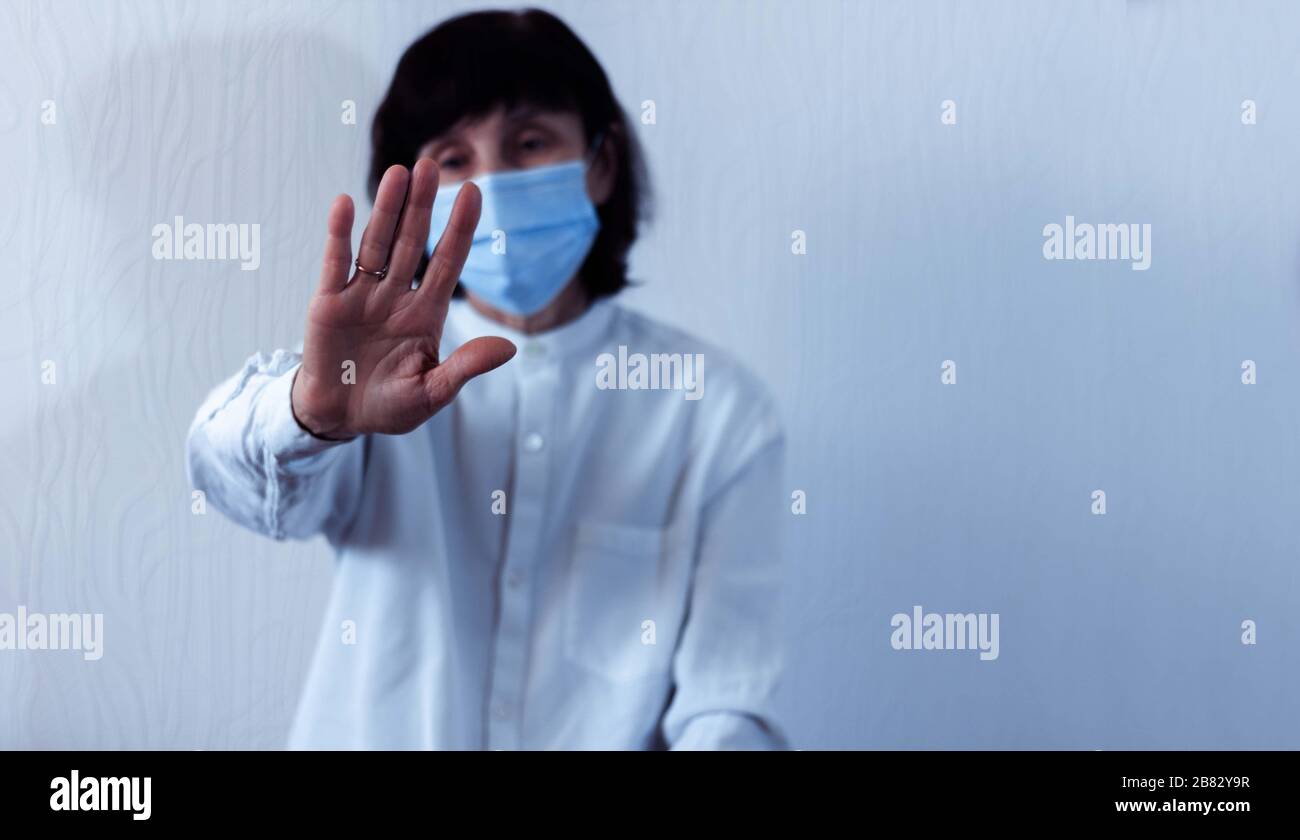 Quarantena del coronavirus e inquinamento atmosferico pm2.5 concetto. Vecchia donna malata che indossa maschera respiratore blu per proteggere con braccio allungato. Wuhan, Cina ep Foto Stock