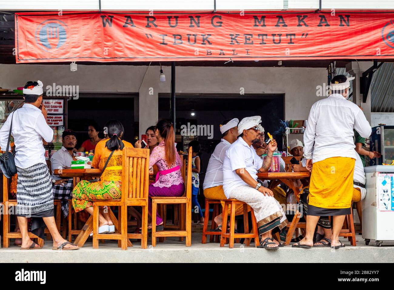 Un gruppo di persone indù balinesi che siedono presso UN ristorante, il Tempio di Besakih, Bali, Indonesia. Foto Stock