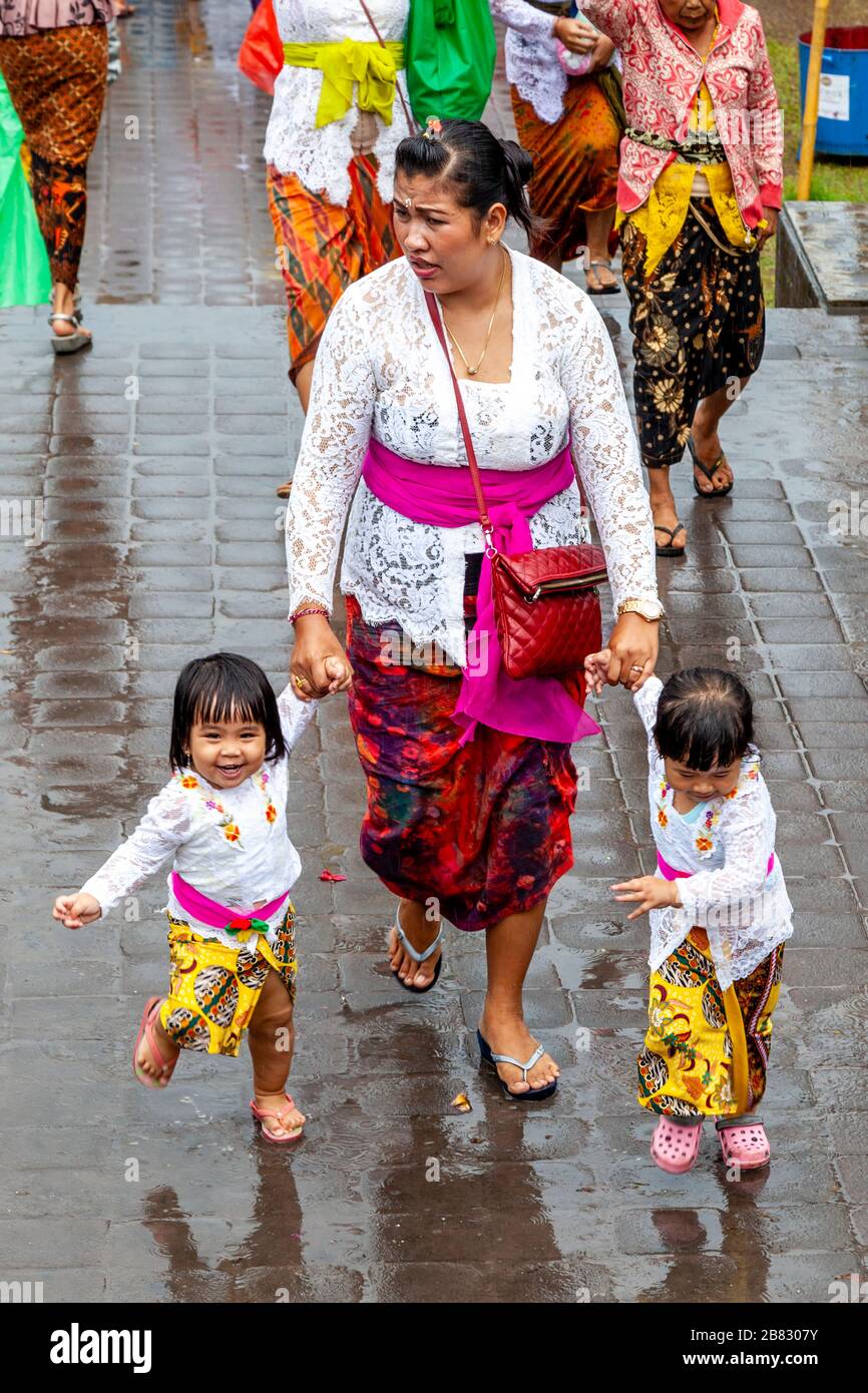 Una famiglia indù balinese arriva alla cerimonia di Batara Turun Kabeh sotto la pioggia, al Tempio di Besakih, Bali, Indonesia. Foto Stock