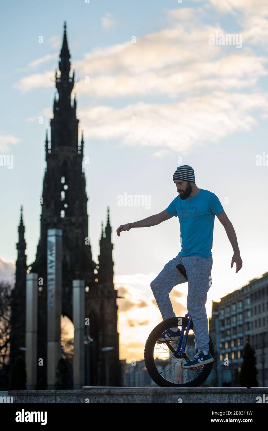 Edimburgo, Regno Unito. 19 Mar 2020. Nella foto: Andrew Buchan, una stunt e un estremo unicista passa il tempo durante quella che normalmente sarebbe un'ora di punta a Edimburgo, ma a causa della pandemia di Coronavirus il centro della città è estremamente tranquillo. La gente ora è affrontata con fare le cose differenti con il loro tempo durante l'isolamento di auto. Lo Scott Monument si trova sullo sfondo, un importante punto di riferimento di Edimburgo. Credit: Colin Fisher/Alamy Live News Foto Stock