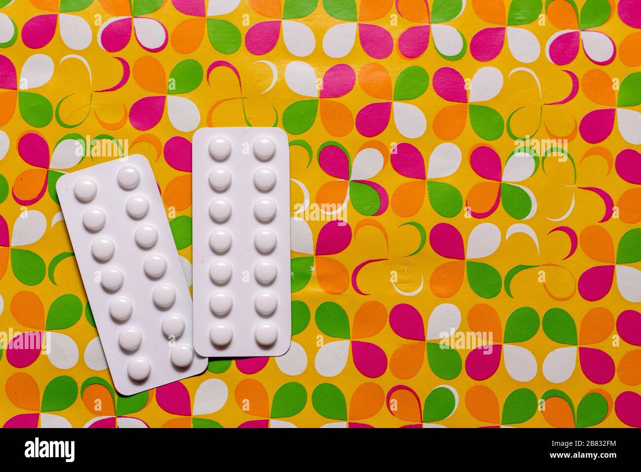 Due pacchetti di pillole bianche su sfondo giallo personalizzato, concetto di farmaci e medicina. Foto Stock