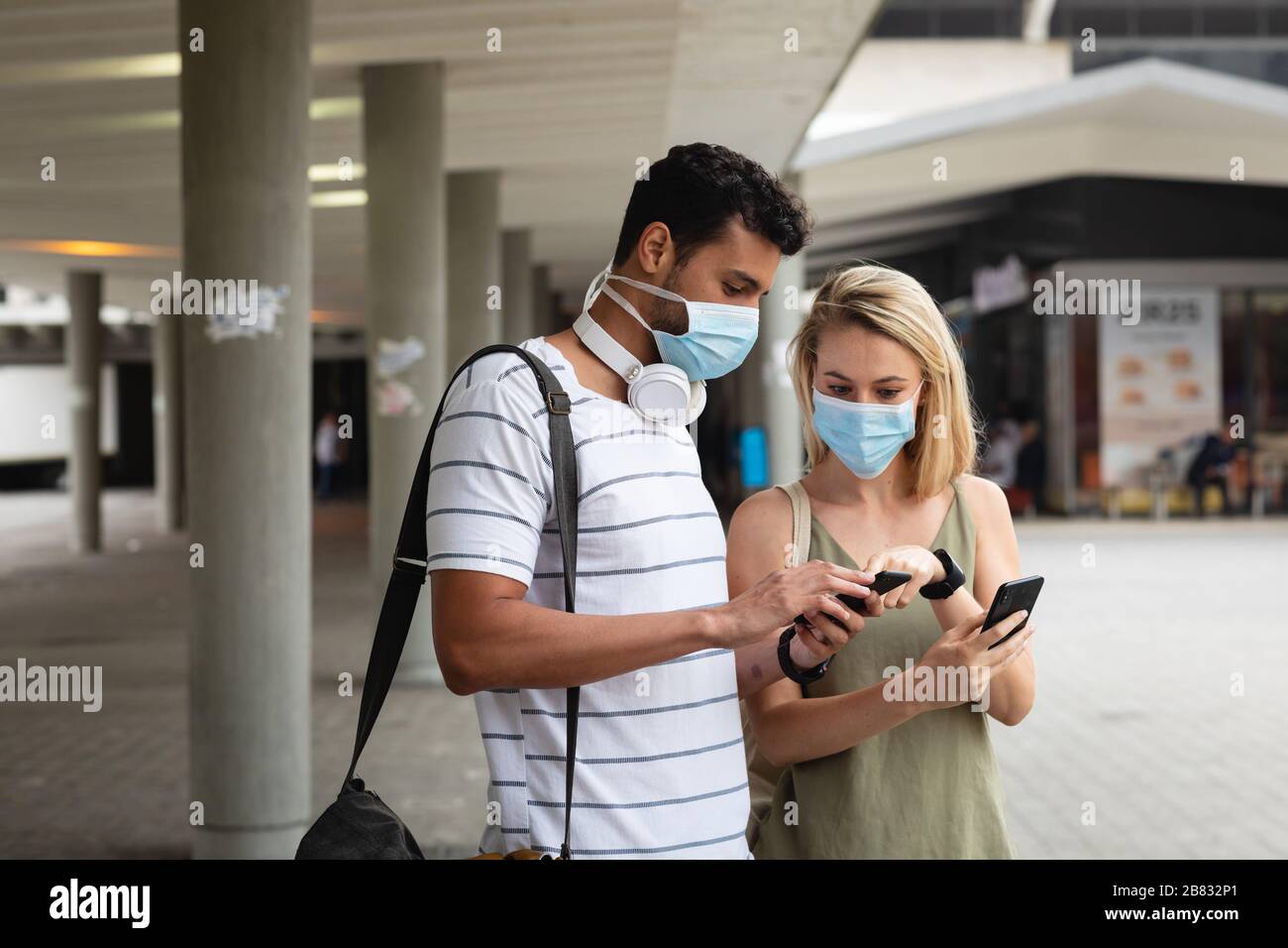 Coppia caucasica in movimento indossando una maschera coronavirus covid19 e guardando i loro telefoni Foto Stock