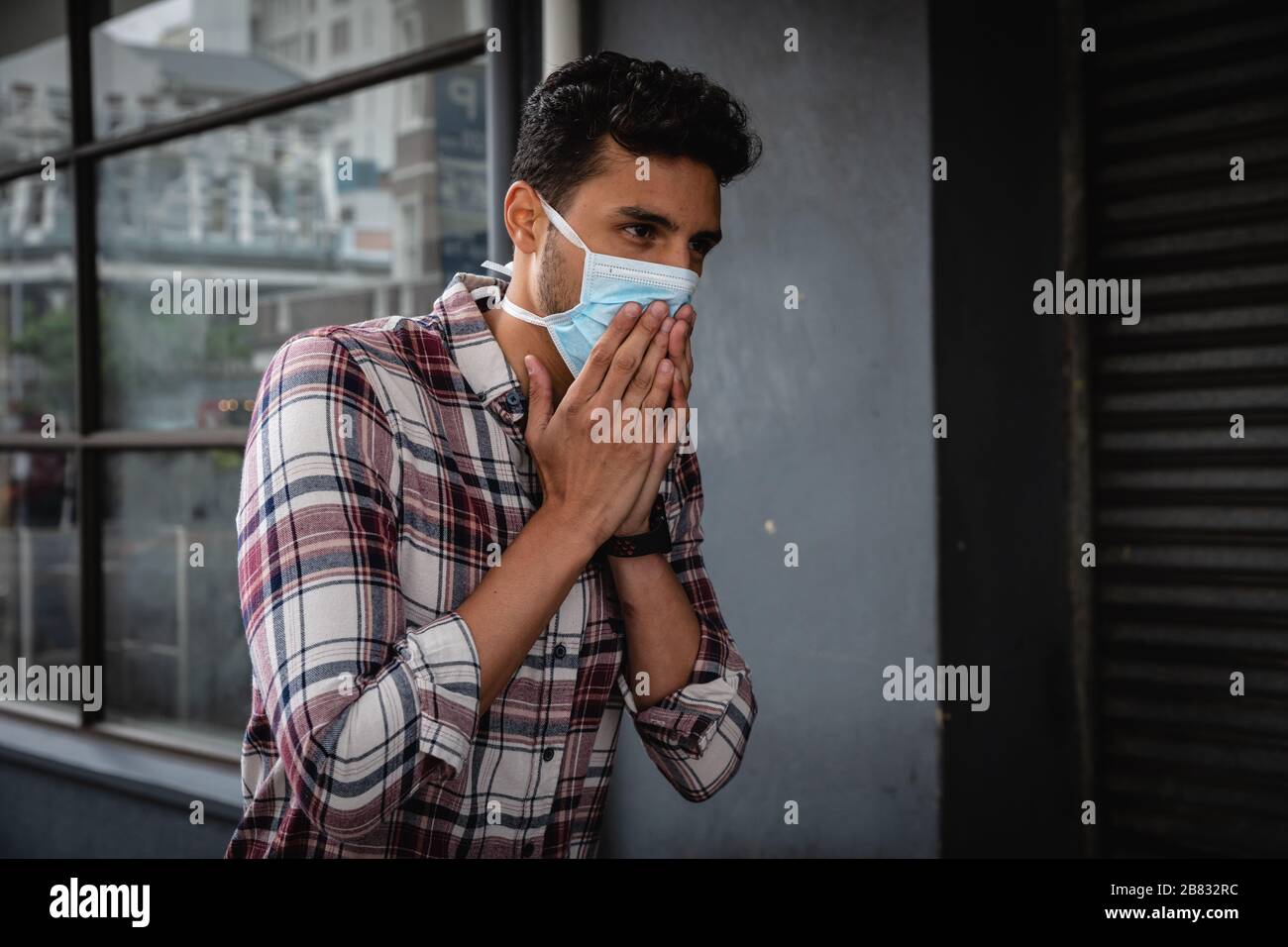 Uomo caucasico che indossa una maschera coronavirus covid19 fuori e tossisce Foto Stock