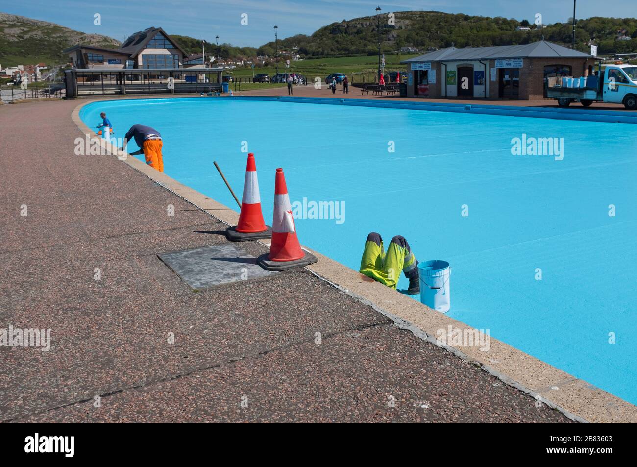 Gli operai dipingono una piscina blu sul lungomare di Llandudno, Conwy, Galles. Foto Stock