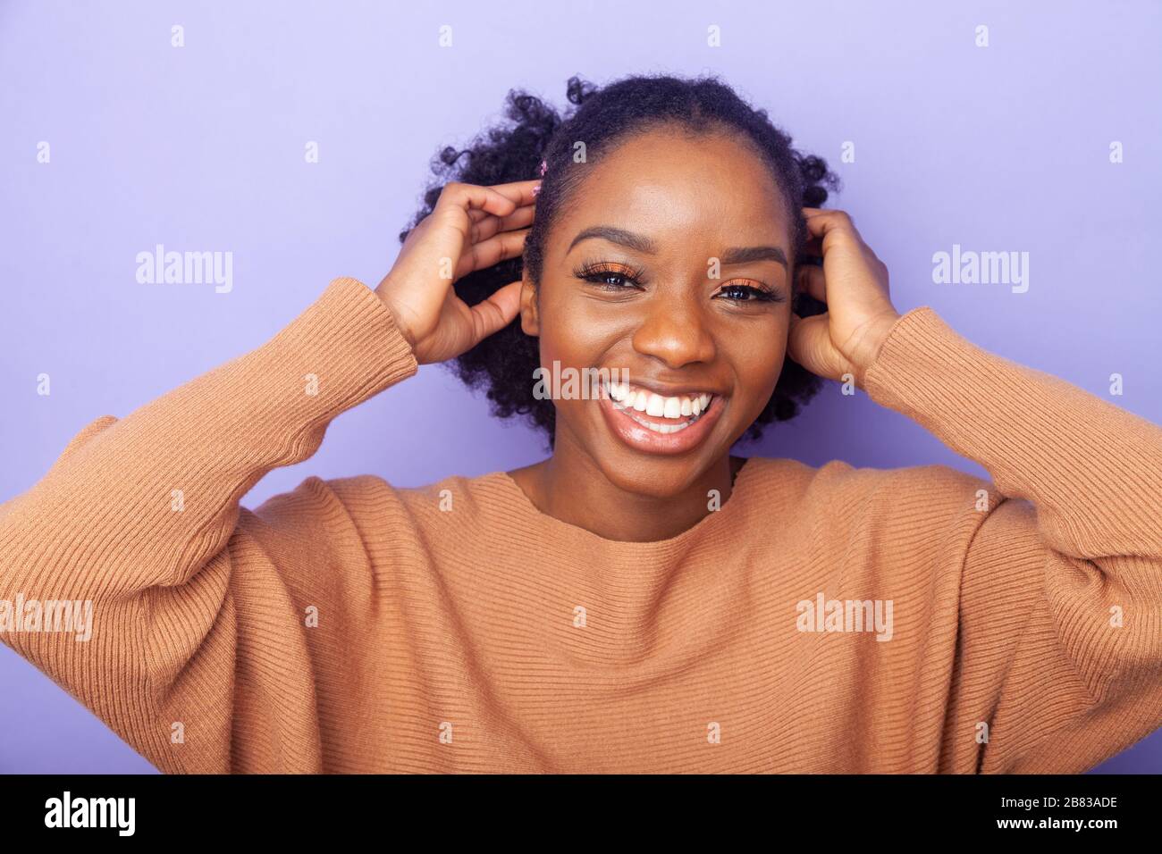 giovane donna allegra con le mani accanto alla testa Foto Stock