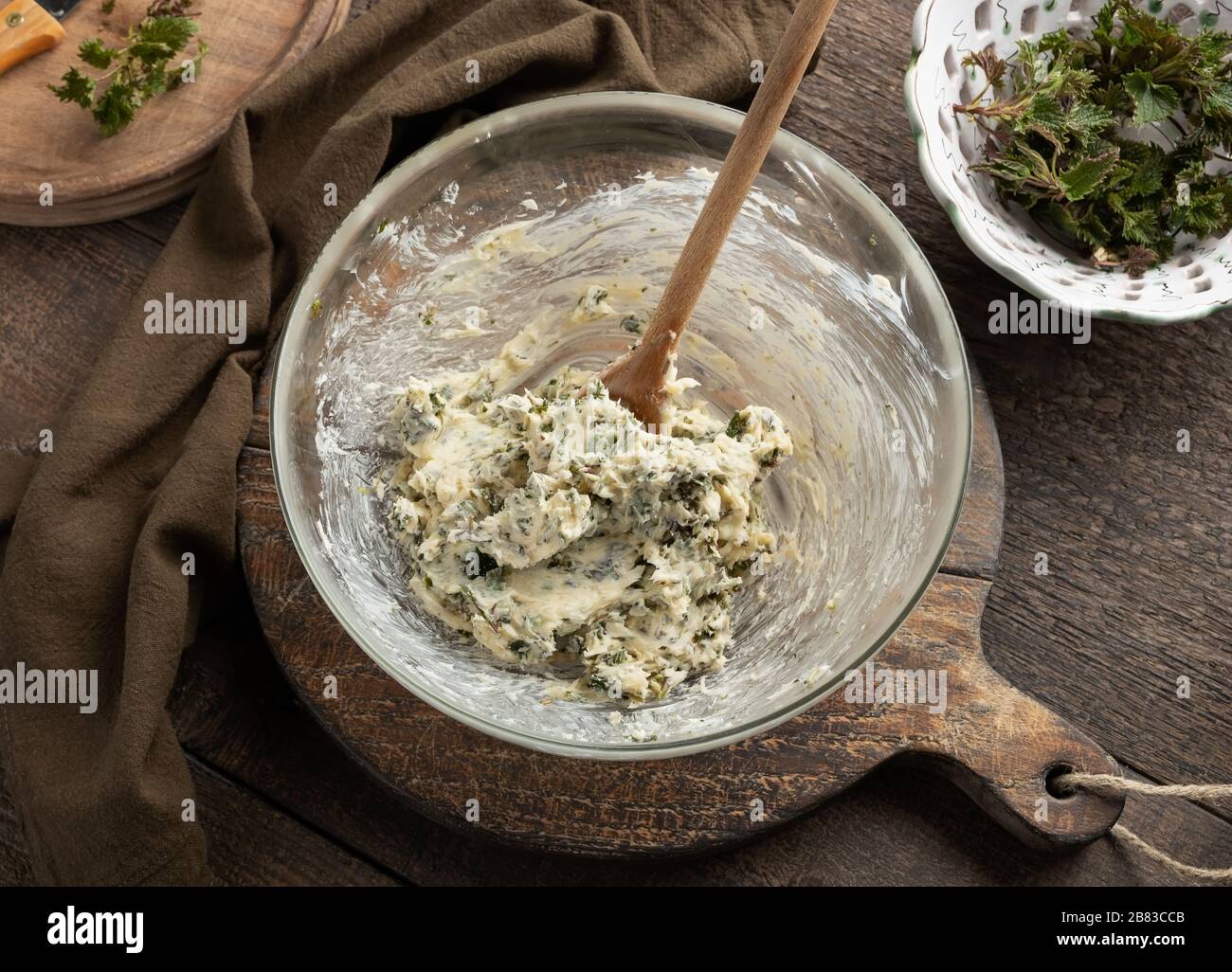 Mescolando il burro e le ortiche giovani tritate raccolte all'inizio della primavera per preparare un pane spalmato Foto Stock