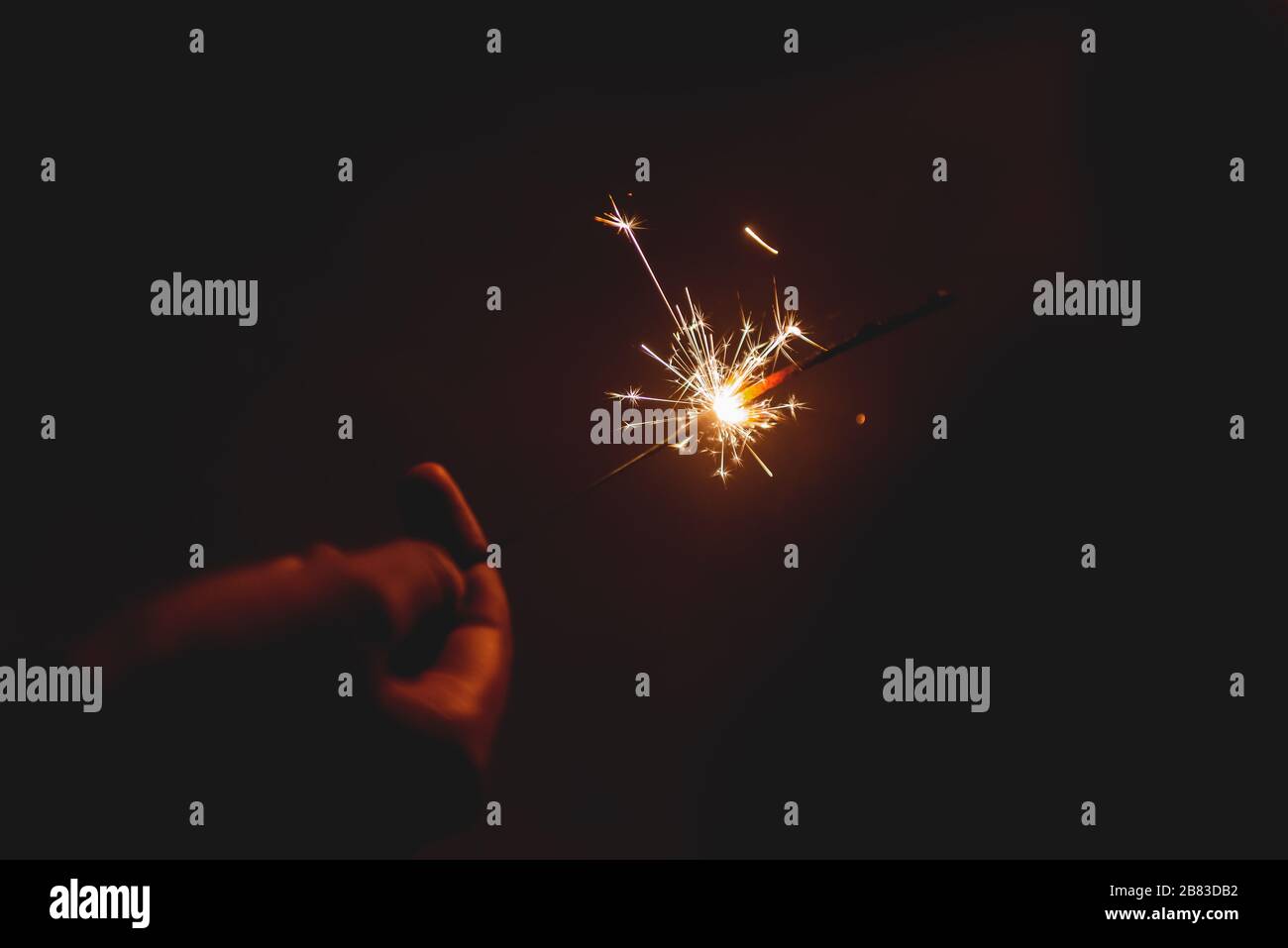 Brucia bastone Starlight fuochi d'artificio pirotecnico nero scuro caldo sfondo tenuto a portata di mano Foto Stock