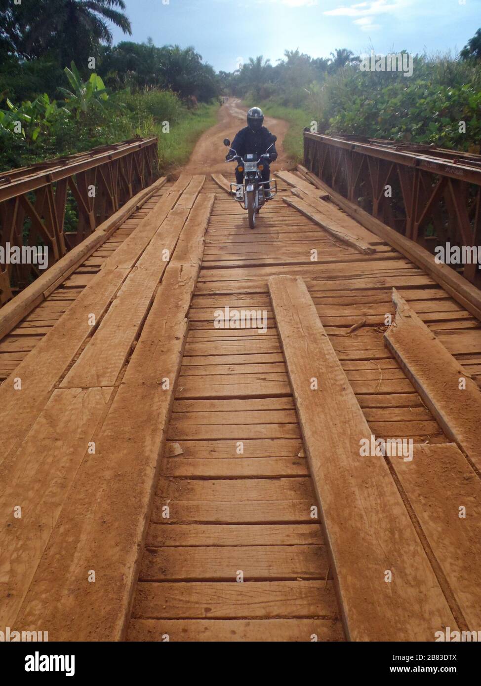 Moto che attraversa un ponte di travi dilapidati DRCongo Foto Stock