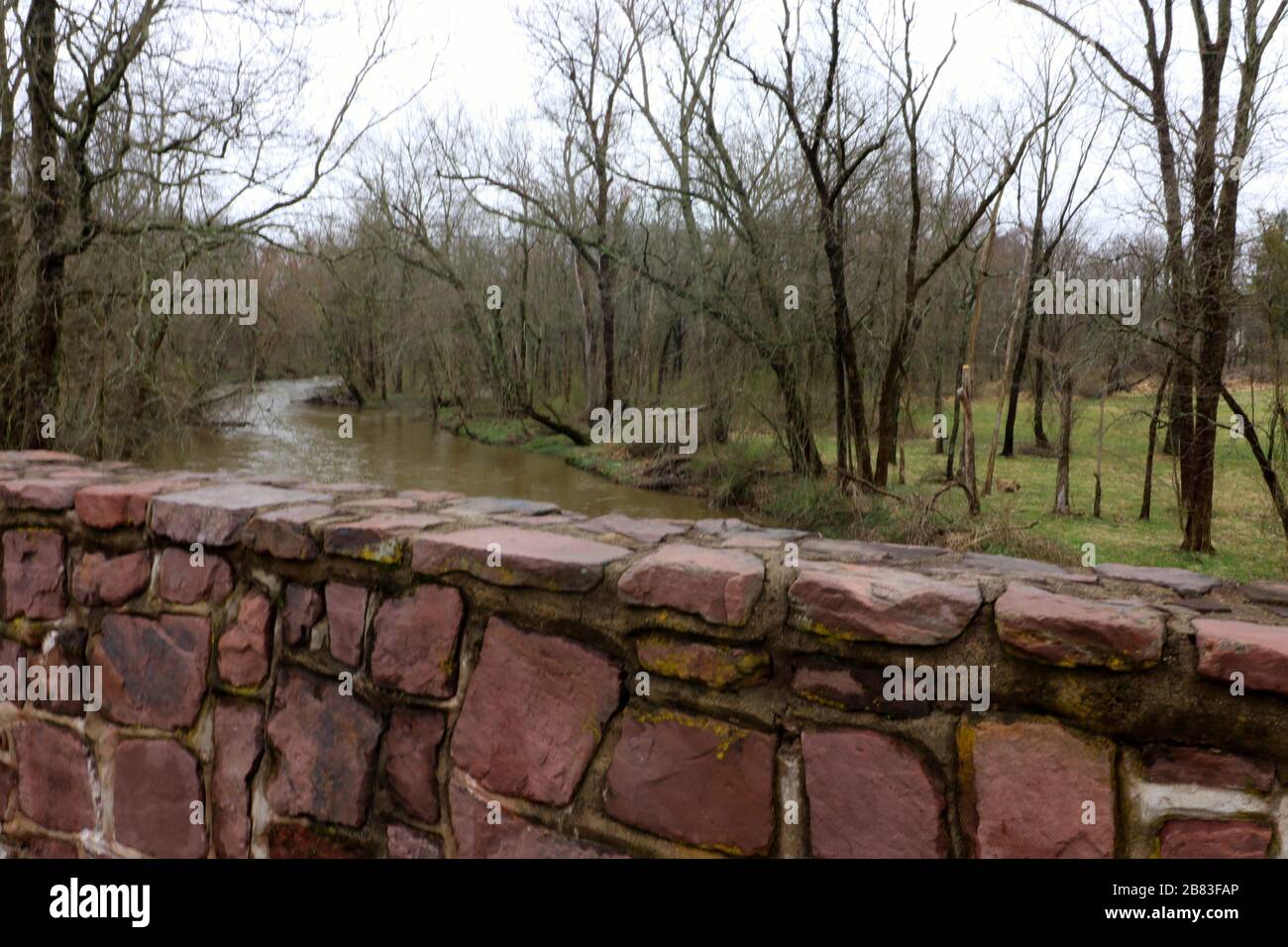 Si può vedere il fiume dietro il muro di pietra su questo vecchio ponte. Foto Stock