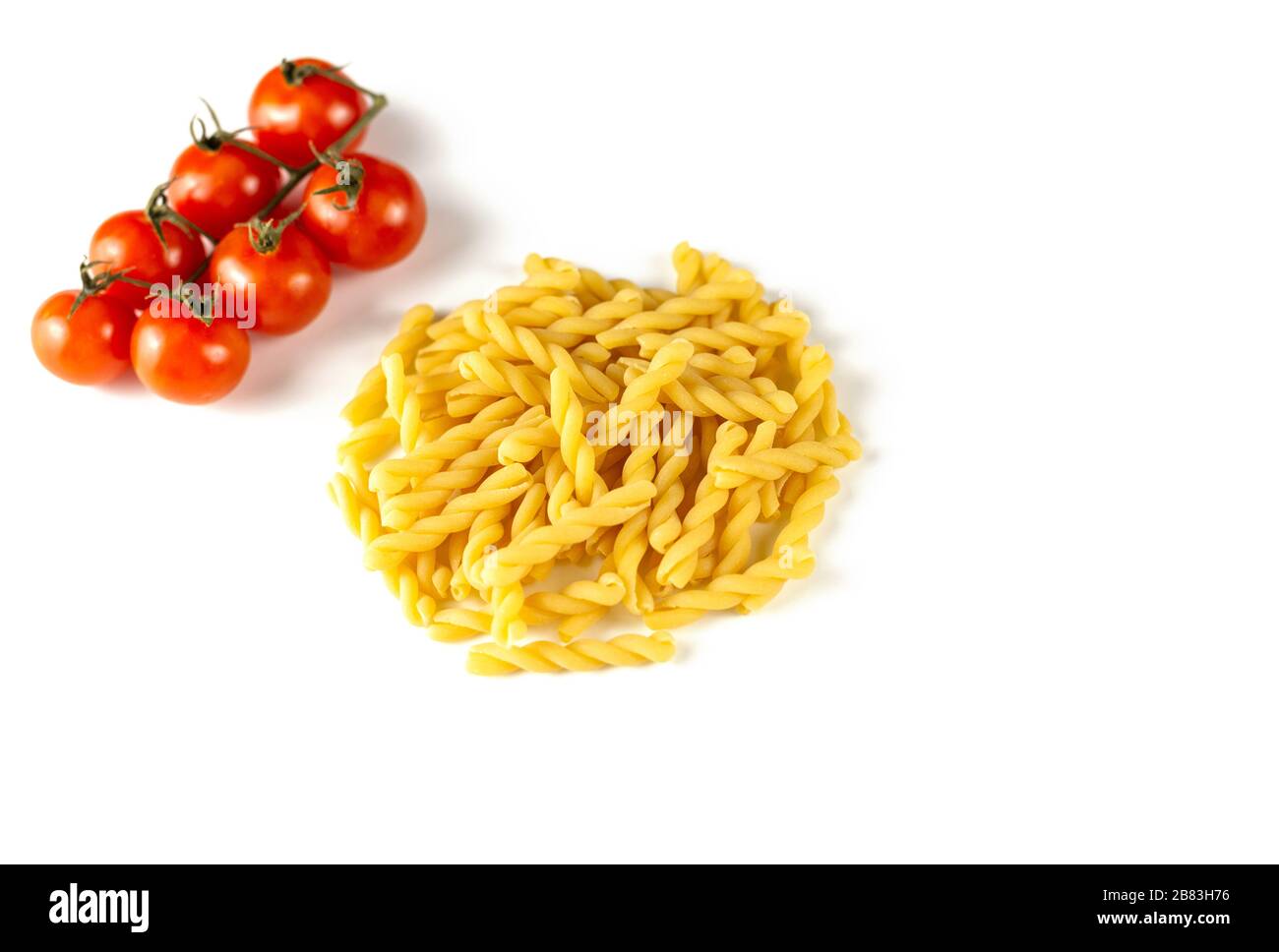 Pasta italiana cruda con tomati di strega isolati su sfondo bianco. Concetto di cibo e bevande. Vista dall'alto. Spazio di copia Foto Stock