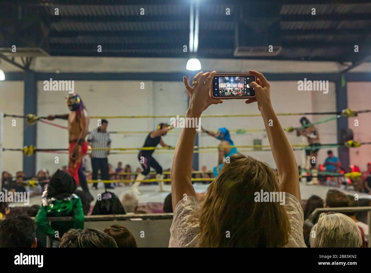 Oaxaca de Juárez, Oaxaca, Messico - una donna fotografa una marcia di lotta Lucha Libre con il suo cellulare. Foto Stock